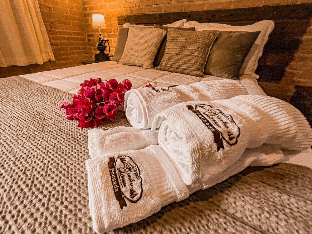 Cama com toalhas bordadas e flores no Minha Glória