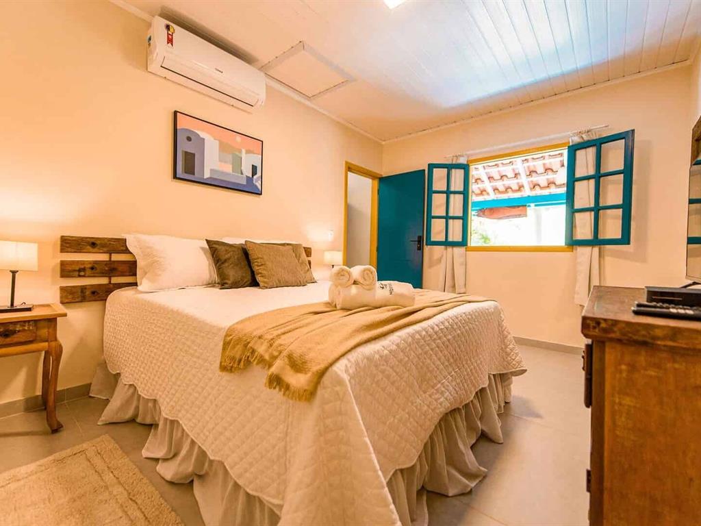 Quarto com cama de casal e janelas de madeira