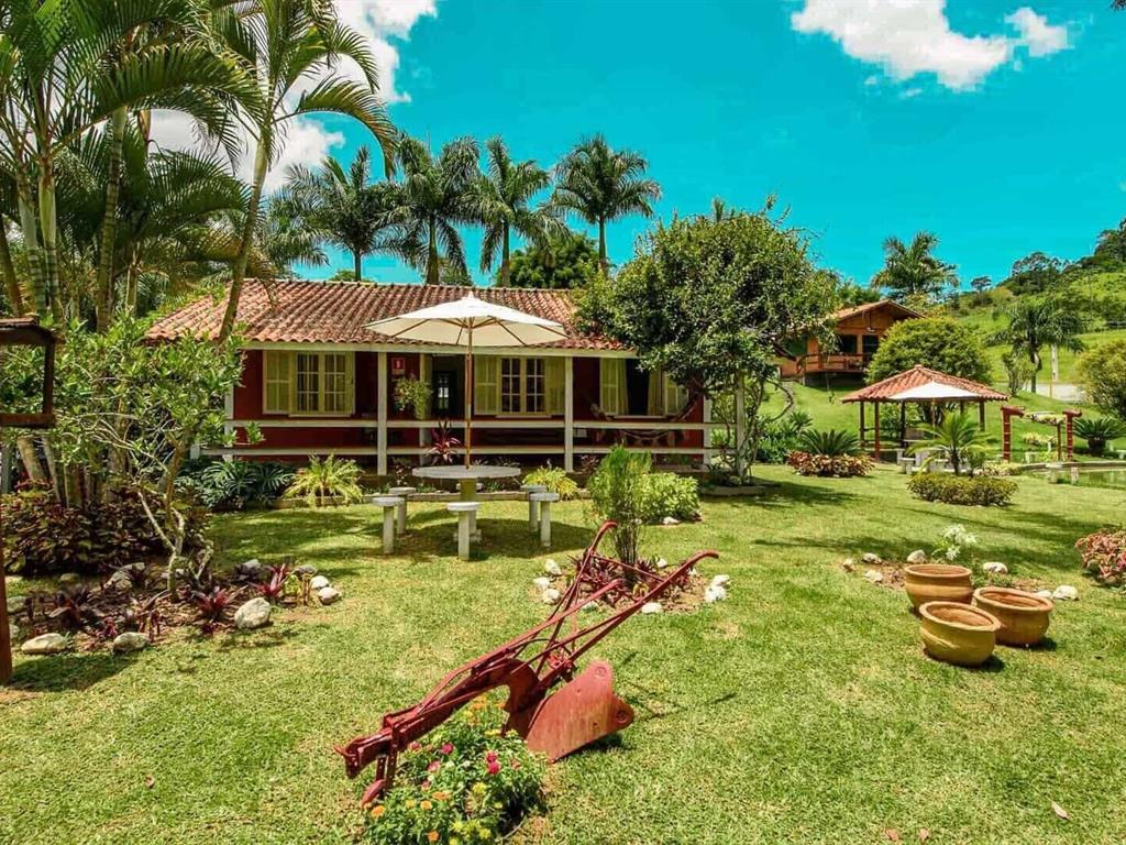 Jardim com casa de fazenda e antigo arado no gramado