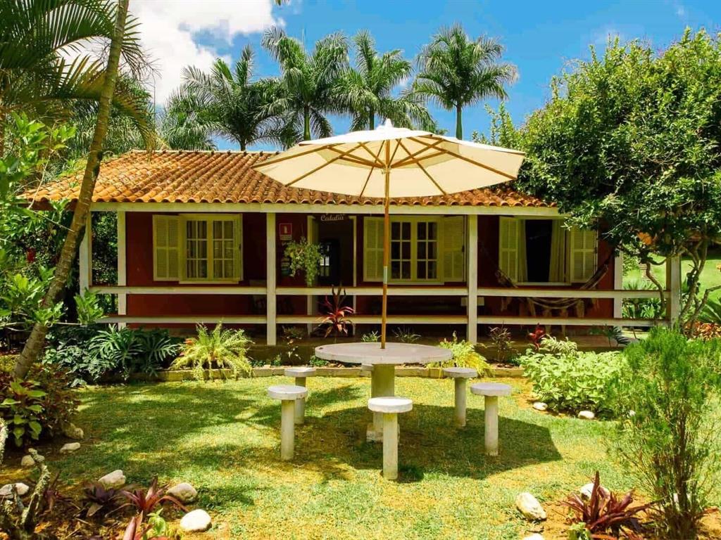 Casa de fazenda com varanda cercada por jardins