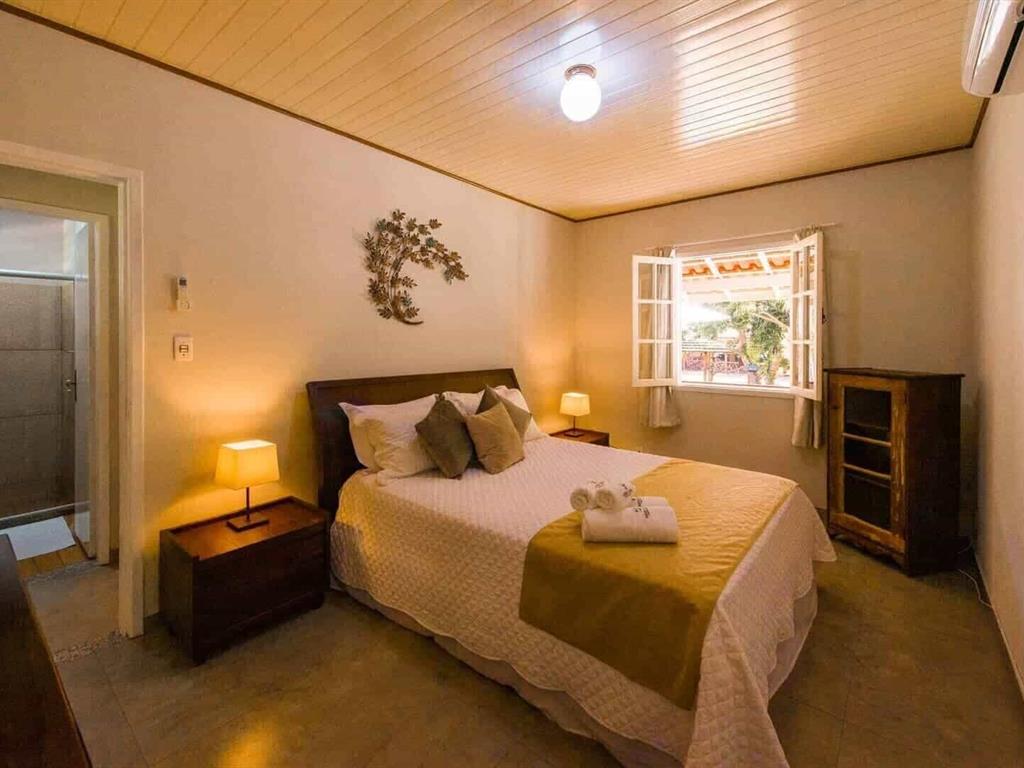Quarto com cama de casal e janelas de madeira