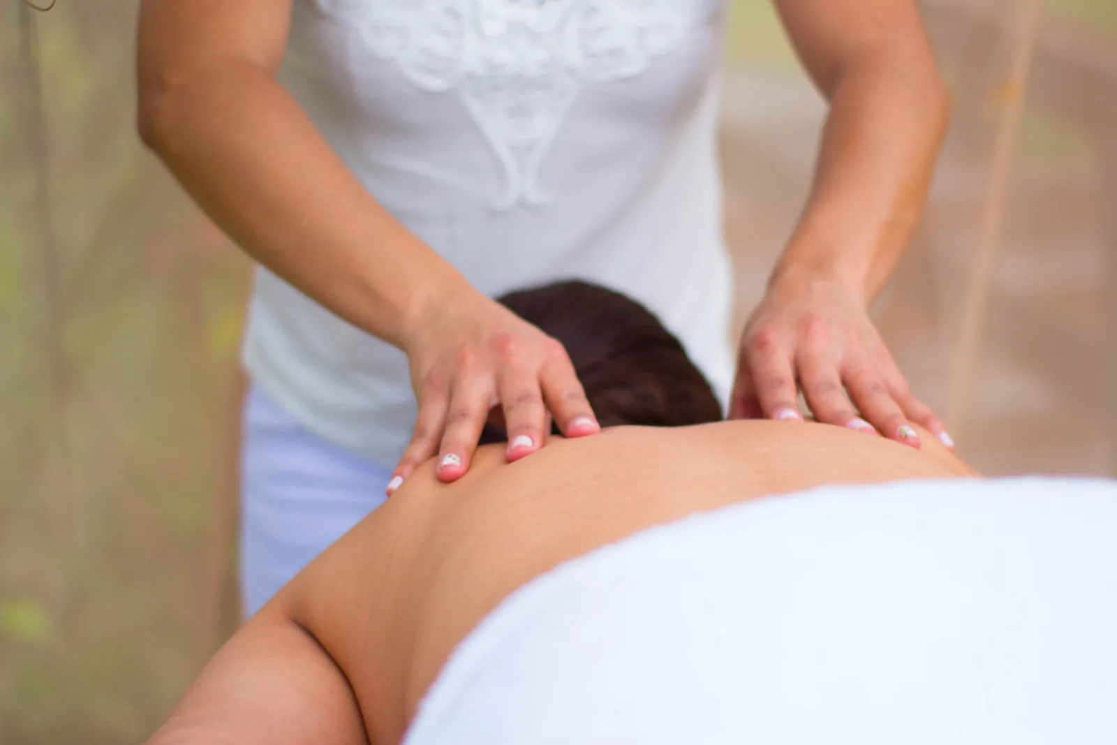 Mãos realizando uma massagem nas costas