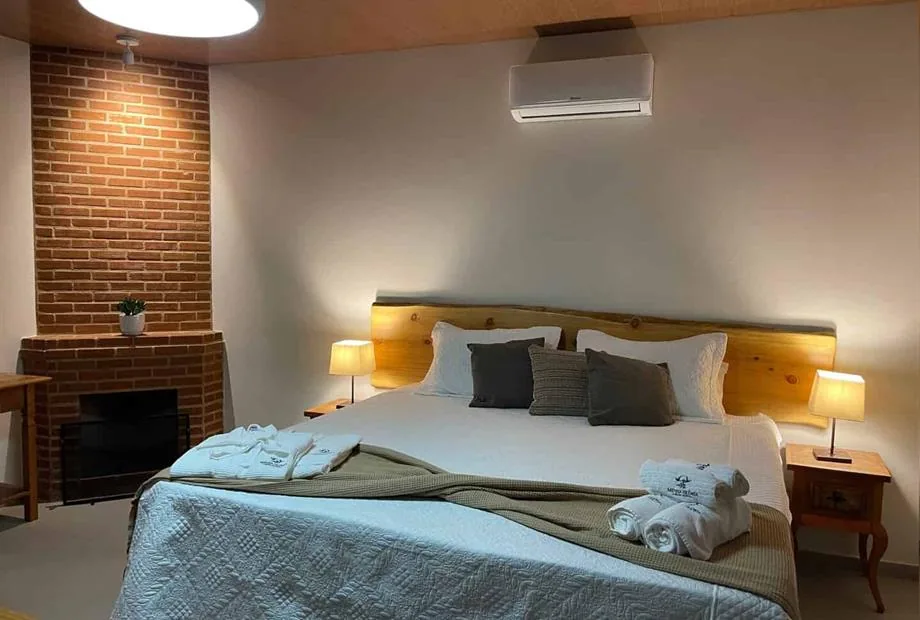 Cama de casal com iluminação lateral e parede revestida de madeira
